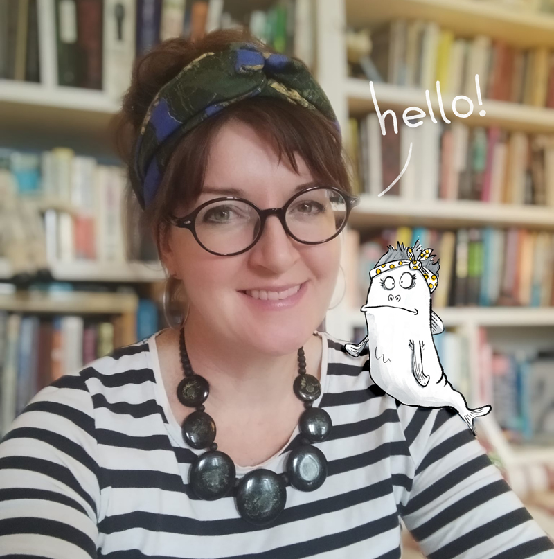 photo of award winning illustrator and cartoonist Dotti Colvin, smiling at camera, with a drawing of Moomafish on her shoulder